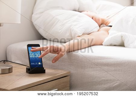 Woman Sleeping On Bed Snoozing Alarm On Smart Phone Screen