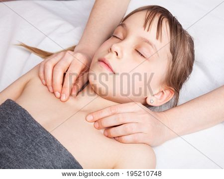 Elementary age girl's collarbones being manipulated by osteopathic manual therapist or physician