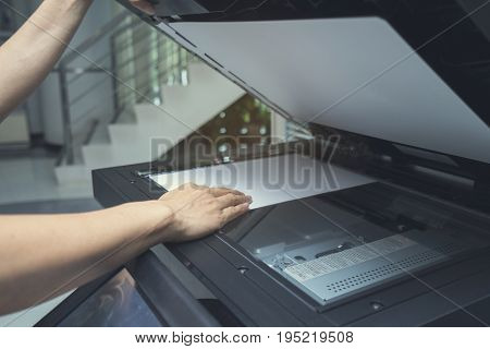 woman hand putting a sheet of paper into a copying device