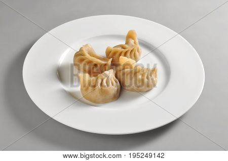 Round dish with Chinese steamed ravioli Jiaozi isolated on grey background
