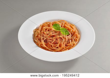 Round dish with a serving of spaghetti with tomato souce isolated on grey background