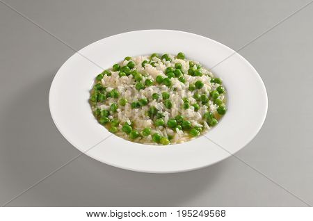 Round dish with boiled rice and peas isolated on grey background