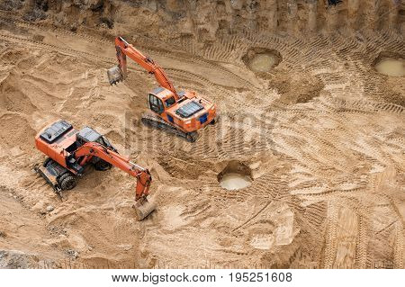 Excavators at sandpit during earthmoving works. Construction of concrete foundation of new building