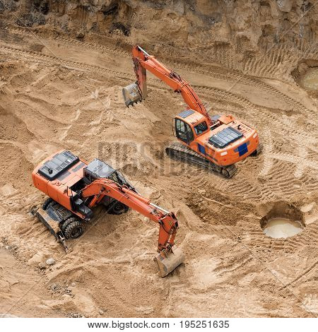 Excavators at sandpit during earthmoving works. Construction of concrete foundation of new building