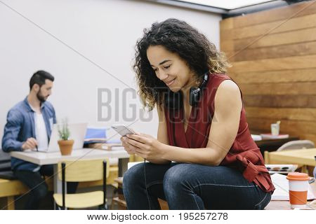 Young woman chatting with her smartphone in coworking espace