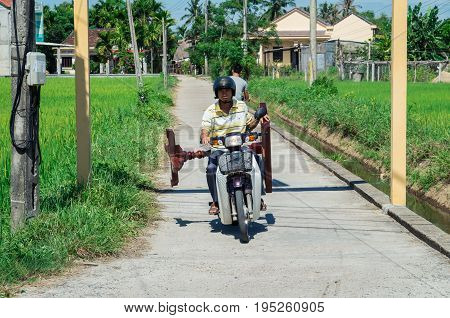 Hoi An - August 15, 2015: a Vietnamese man transporting a wooden table on a motorscooter.