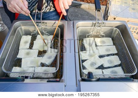 Agno, Switzerland - 12 March 2016: Street vendor while he is cooking the tasty pancakes dipped in boiling oil