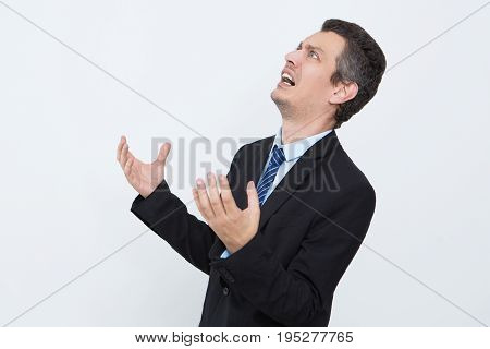 Frustrated businessman shocked with news. Stressful young entrepreneur depressed because of failure. He crying and looking up opposite white background. Despair concept