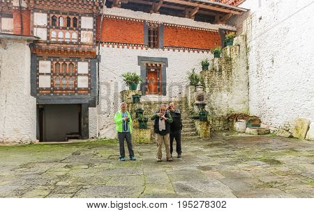 Trongsa Bhutan - September 12 2016: Three Caucasian men taking photos in the courtyard of Trongsa Dzong Bhutan