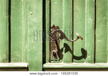 Old green and grunge wooden entrance door with antique door handle.