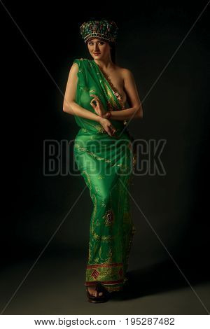 Indian female in vintage beaded semi-precious stones perak cap adornment ornament paduka antique footwear and green sari Ladakh India