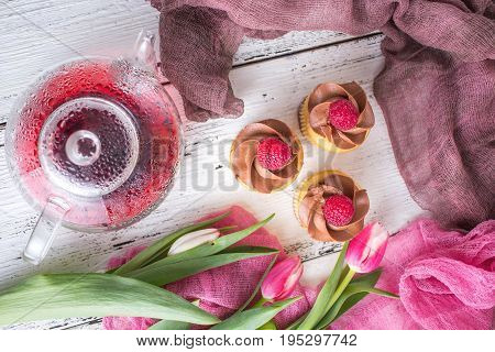 Spring background. Cupcakes and tea on a table with pink tulips. Still life with fresh bouquet of tulips. concept of a ladies' tea drinking. Morning tea with cupcakes.