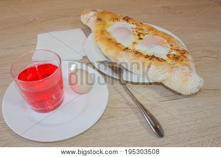 Khachapuri on ajarski - recipe of Georgian cuisine. Adjarian Georgian national dish Khachapuri bread with cheese and egg on a plate in a cafe