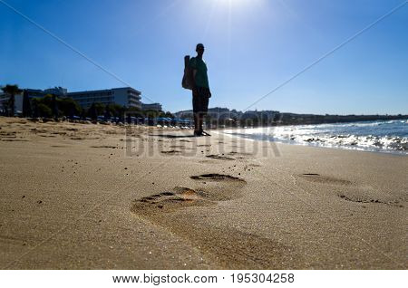 Footprints on the beach close up. Silhouette of a person walking on the beach barefoot