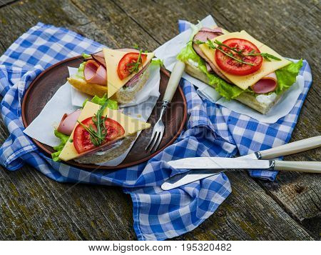 Sandwich with ham, cheese and tomato on plate and on table