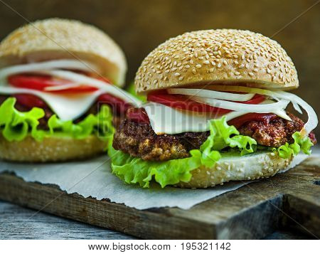 Close-up on big tasty hamburgers on wooden table