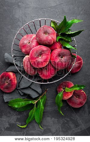 Peaches with leaves on dark background, top view