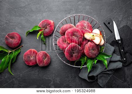 Peaches with leaves on dark background, top view