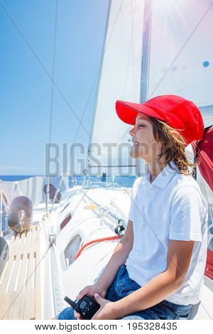 Cute boy captain on board of sailing yacht on summer cruise. Travel adventure, yachting with child on family vacation. Kid clothing in sailor style, nautical fashion.