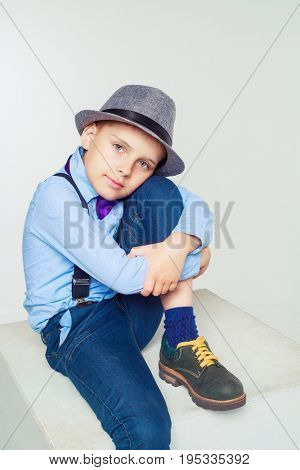 happy stylish boy wearing a hat and a tie, against white background