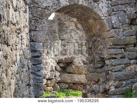 arch of gray stone old building way out of it on a stone masonry labyrinth amid the ruins