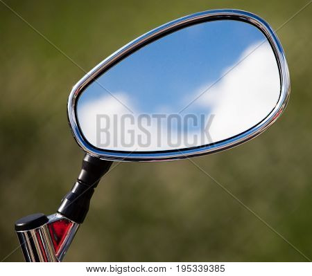 Reflection of clouds on a blue sky in a motobike mirror .