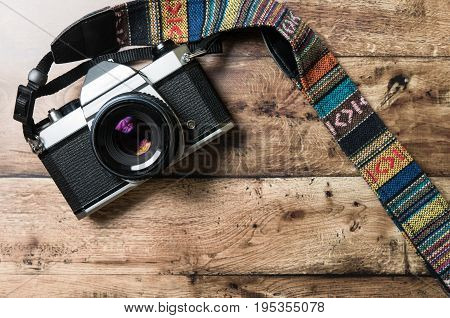 Old analog camera with vintage strap on a wooden desk