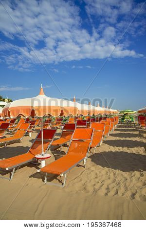 Orange umbrellas and chaise lounges on the beach of Rimini in Italy - the destination in the Adriatic coast of Emilia-Romagna