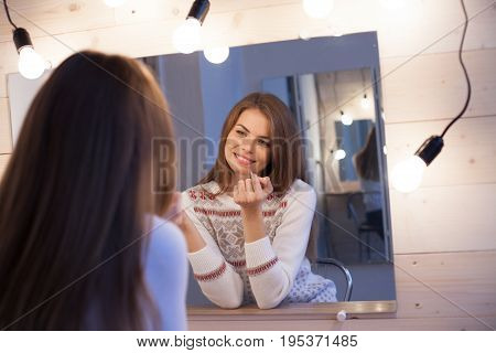 beautiful girl stands before the mirror and makes makeup 1
