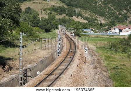 Iberian gauge railway track between Leon and Gijon on its way through La Pola de Gordon, Leon Province, Spain. In the background can be seen the town of Puente de Alba