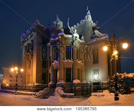 Illuminated House with Chimaeras or Horodecki House. Night scene. Building and street are powdered with snow.