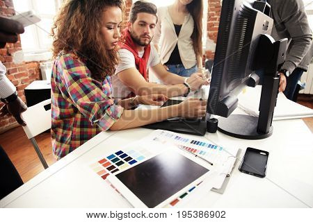 Teamwork concept.Young creative coworkers working with new startup project in modern office.Group of people analyze data on desktop computer.