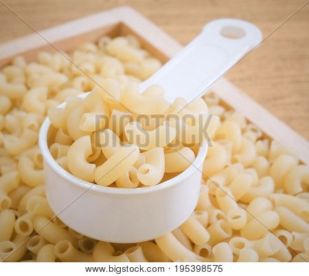 Food and Cuisine Uncooked and Dried Elbow Macaroni or Gomiti Pasta in Plastic Measuring Cup.