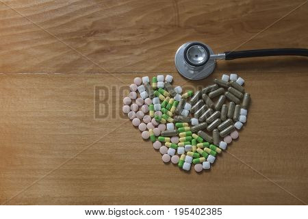 Drug pills in various shape and sizes on wooded table space for text Headphones doctor
