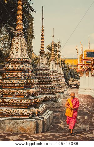 BANGKOKTHAILAND-MAY 172017: Thai monk is walking in front of old ancient pagoda at Wat Pho Temple in Bangkok Thailand.