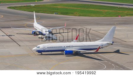 Two Airplanes Taxiing At The Airport, On The Steering Track, And The Gangplank