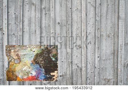 A fragment of a wall built from rhythmically spaced boards and battens with located on the background of the artist's palette.