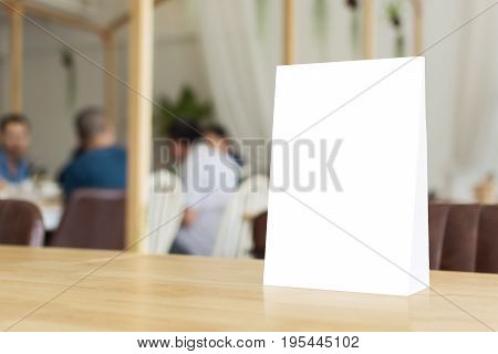 Mock up blank template menu frame on wood table in restaurant with blurred background Clipping path included