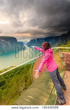 Tourist woman on Stegastein viewpoint enjoying Aurland fjord view in evening time Sogn Og Fjordane Norway