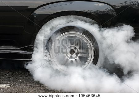 Drag racing car burns rubber off its tires in preparation for the race .