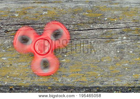 Popular Tri Fidget Hand Spinner Spinning On Old Wooden Board.