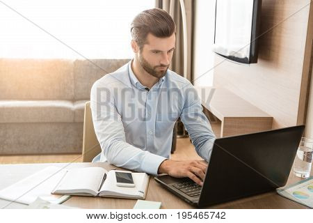 Young male business traveler hotel accomodation working