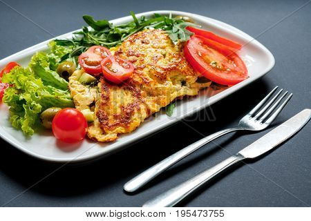 Salad of fried tofu with tomatoes and rocula. Homemade vegetarian salad in a white plate on a black background. A healthy Asian diet vegan vegetarian salad