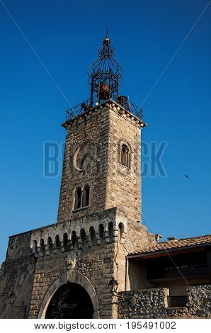 Close-up of old stone tower at sunrise, with clock and bell, in the city center of the quiet village of Le Thor. Located in the Vaucluse department, Provence-Alpes-Côte d'Azur region in southeastern France