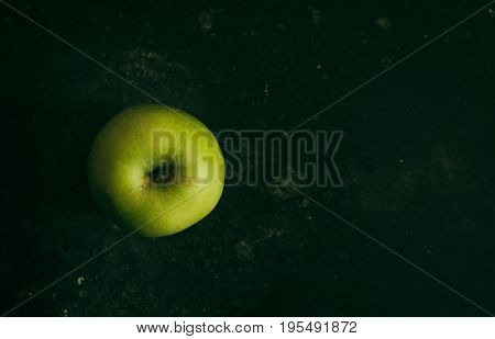 Fresh and delicious green apple picked from a nearby farmer's market, placed on a dark background.