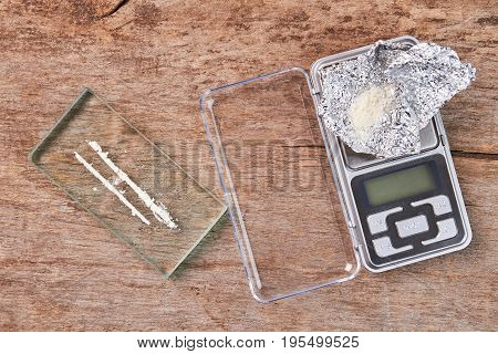 Narcotics, digital scales, wooden background. White powder, glass, scale, foil, old wooden floor.