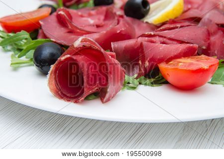 a dish of bresaola and fresh aragula