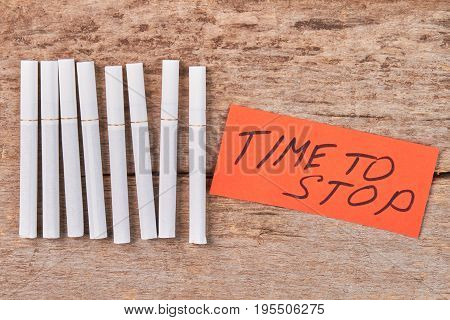Time to stop tobacco smoking. Several lying cigarettes, message, wooden background.