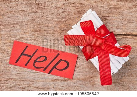 Cigarettes with red ribbon and bow. Cigarettes with red ribbon, red message help, old wooden background.