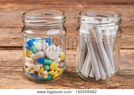 Pills and cigarettes in different jars. No cigarettes and drugs concept.